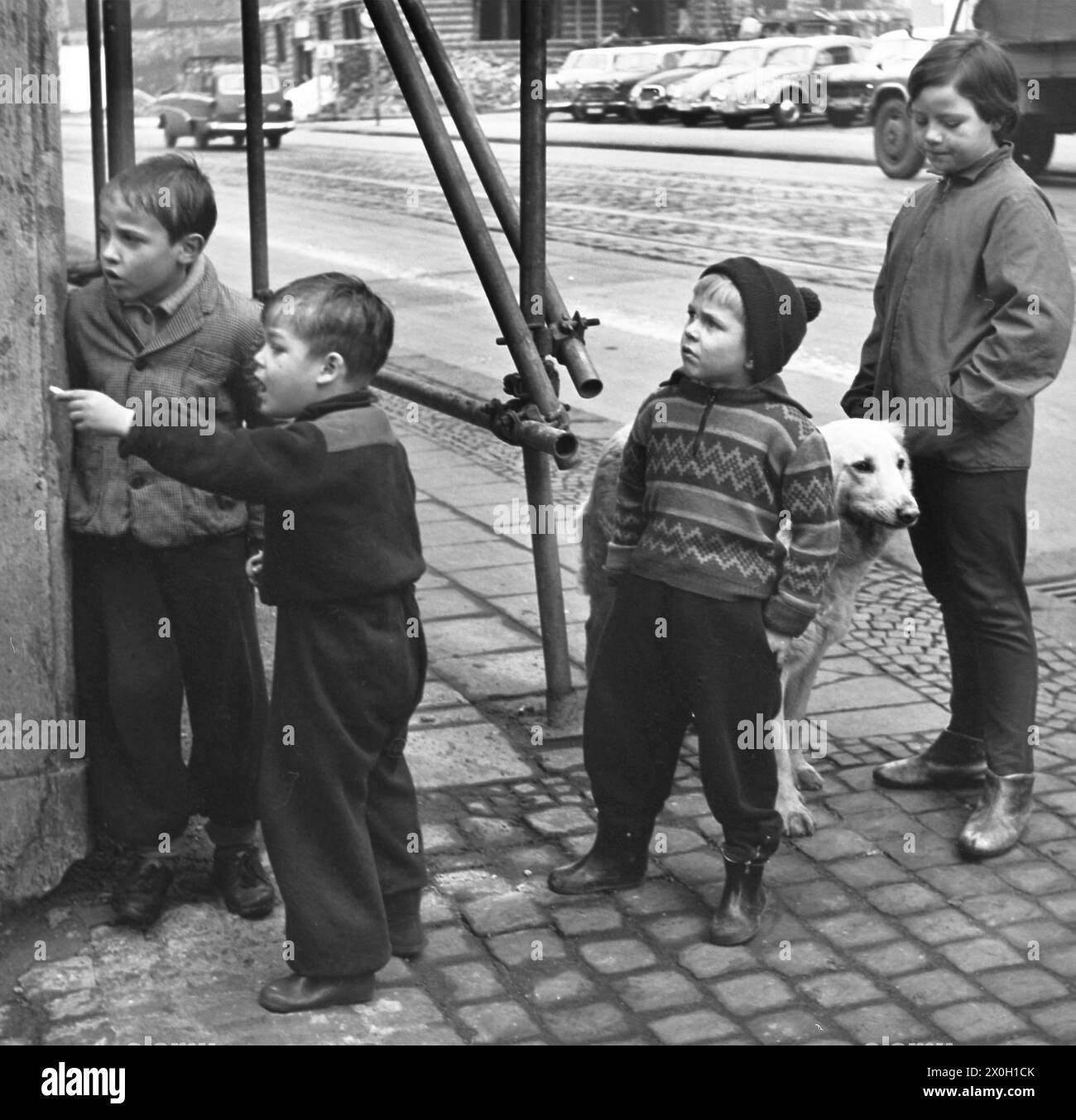 I bambini stanno in piedi in una strada. Nella foto, un ragazzo sta mostrando qualcosa ai suoi compagni di gioco. [traduzione automatizzata] Foto Stock