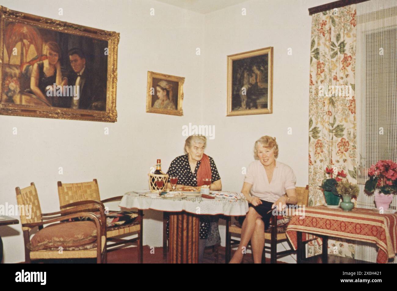 Una donna più anziana e una più giovane siedono ad un tavolo da gioco in un soggiorno. [traduzione automatica] Foto Stock