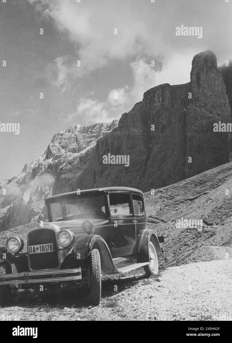 Un'auto della Hupp Motor Car Company è parcheggiata su una strada nelle Dolomiti italiane di fronte ad un massiccio montano. [traduzione automatica] Foto Stock