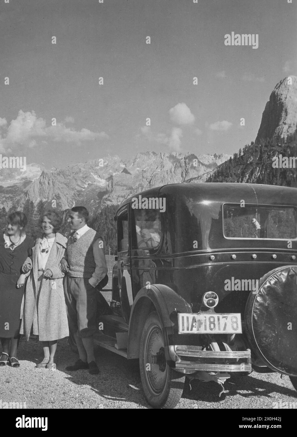 Tre persone si trovano su una strada accanto ad un Hupmobile Serie e nelle Dolomiti italiane. [traduzione automatica] Foto Stock