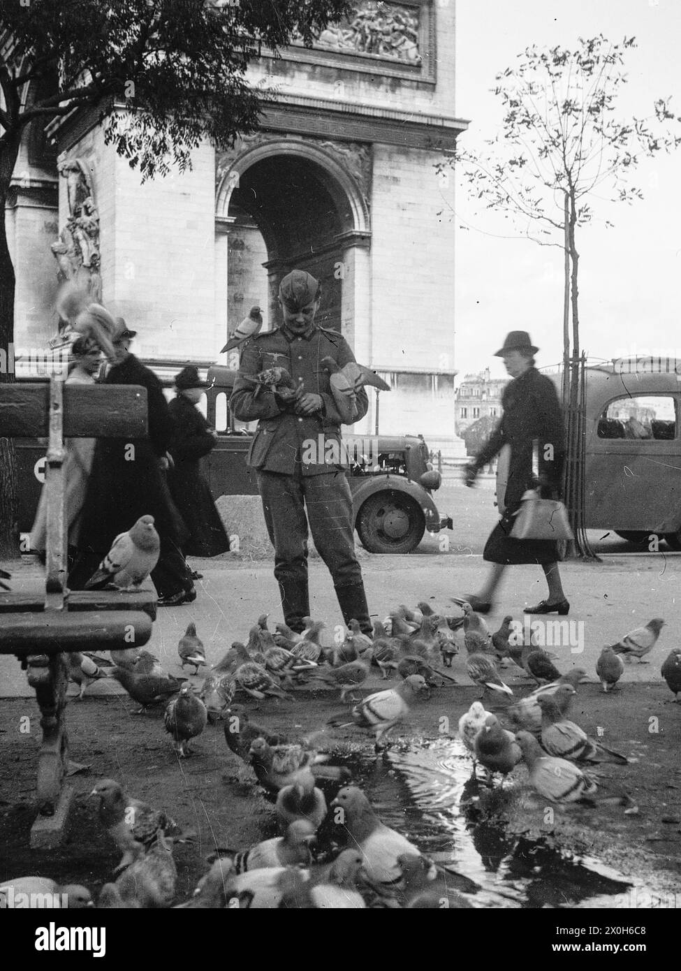 Un soldato della Wehrmacht nutre piccioni all'ombra dell'Arco di Trionfo. La foto è stata scattata da un membro del 154th Infantry Regiment / 58th Infantry Division, in Francia. [traduzione automatizzata] Foto Stock