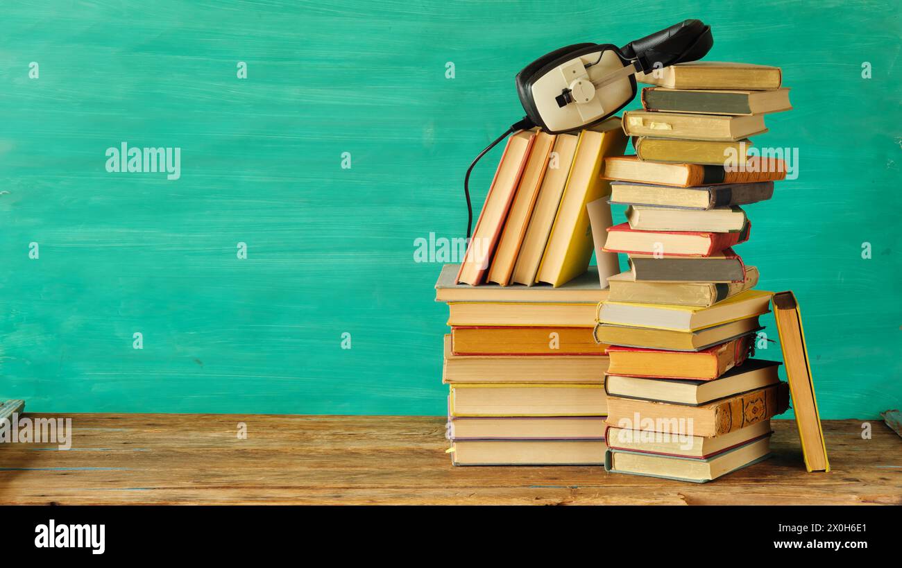Ampia raccolta di libri e afoni, concetto di audiolibri, intrattenimento, istruzione e e-learning su sfondo verde acqua, spazio di copia gratuito. Foto Stock
