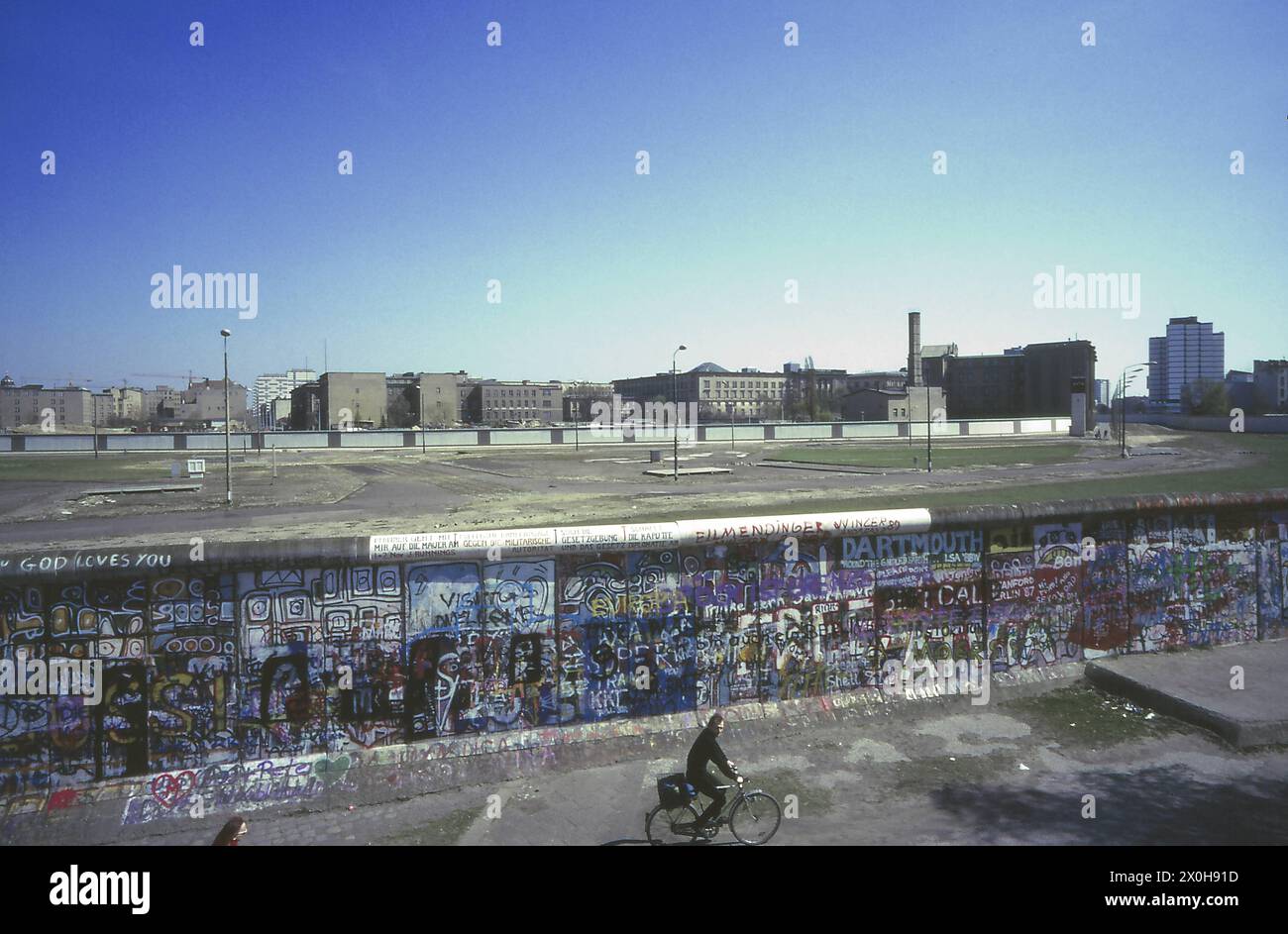 Il muro dipinto con graffiti a Potsdamer Platz. L'ottagono di Leipziger Platz è chiaramente visibile nell'area di confine tra le due mura. Allo stesso modo, gli ingressi recintati alla stazione della metropolitana e alla stazione S-Bahn accanto ad essa, uno dei cui ingressi a Berlino Ovest è chiuso da un pannello sul lato destro. Tutto il resto nella stazione è a Berlino Est. Dopo la riunificazione, non è più possibile vedere senza ostacoli gli ex edifici del governo prussiano. [traduzione automatizzata] Foto Stock