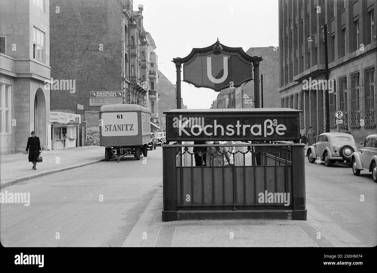 L'immagine mostra l'ingresso alla stazione della metropolitana di Kochstraße lungo Friedrichstraße. È ancora possibile vedere pile di macerie dalle rovine e spazi vuoti tra gli edifici. Anche i pali luce presumibilmente temporanei e le auto del tempo sono interessanti. La targa rivela che l'auto sulla destra è registrata a Berlino Ovest (KB). A quel tempo, i berlinesi dissero che KB significava niente benzina, GB per Berlino Est significava niente benzina. [traduzione automatizzata] Foto Stock