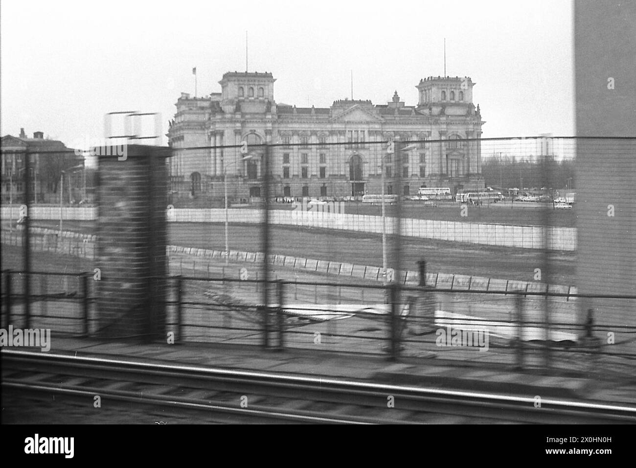 Questa è una foto della storia contemporanea. La S-Bahn e il treno a lunga distanza correvano tra le stazioni di Friedrichstrasse e Lehrter Bahnhof, al confine tra Est e Ovest, per così dire. Si possono vedere le fortificazioni di confine dal lato orientale con recinzioni lungo i binari e le mura fino alla parete finale sulla sponda settentrionale della Sprea. Berlino Ovest iniziò solo sulla riva meridionale della Sprea, appena visibile qui e che fu la rovina dei rifugiati che credevano che il confine fosse in mezzo al fiume. Dietro di esso, il Reichstag rimase senza una nuova cupola per molti anni. [automatizzato Foto Stock