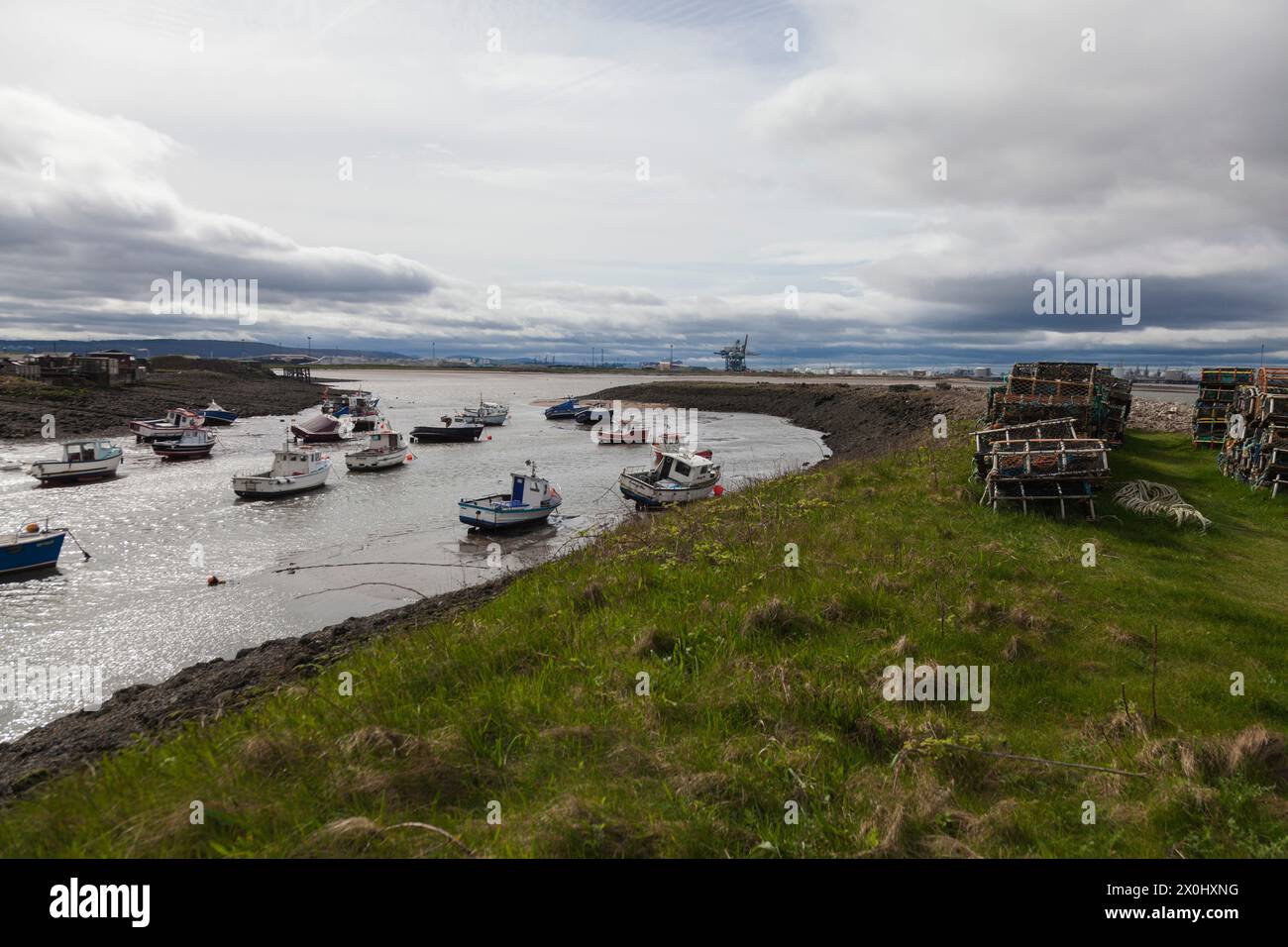 Barche ormeggiate nel porto a Paddys Hole, Redcar, Inghilterra, Regno Unito con Teesport industriale in background Foto Stock