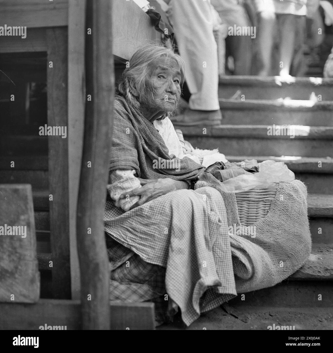 Una vecchia donna a Cuernavaca in Messico è seduta su una scala. Ha un cestino con lei. [traduzione automatica] Foto Stock