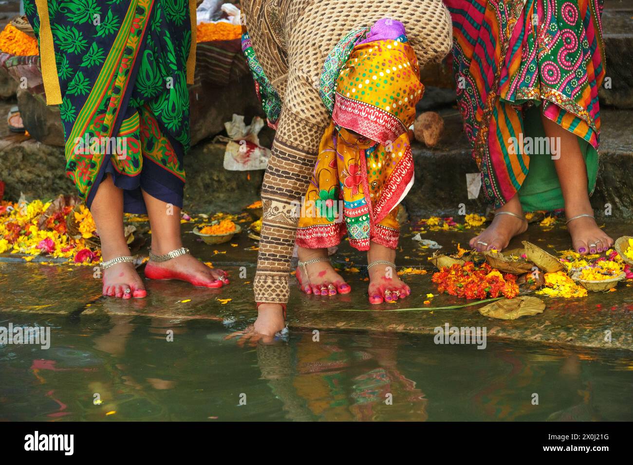 Donna pellegrina che riempie una bottiglia di plastica con acqua del Gange a Varanasi, India. Foto Stock