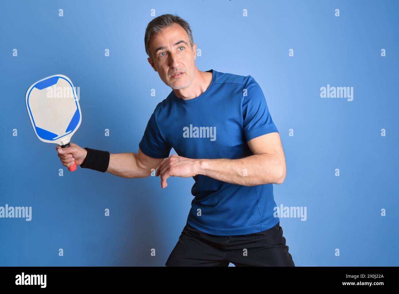 Ritratto di un giocatore di pallacanestro concentrato in attesa di colpire una palla su sfondo blu isolato. Foto Stock