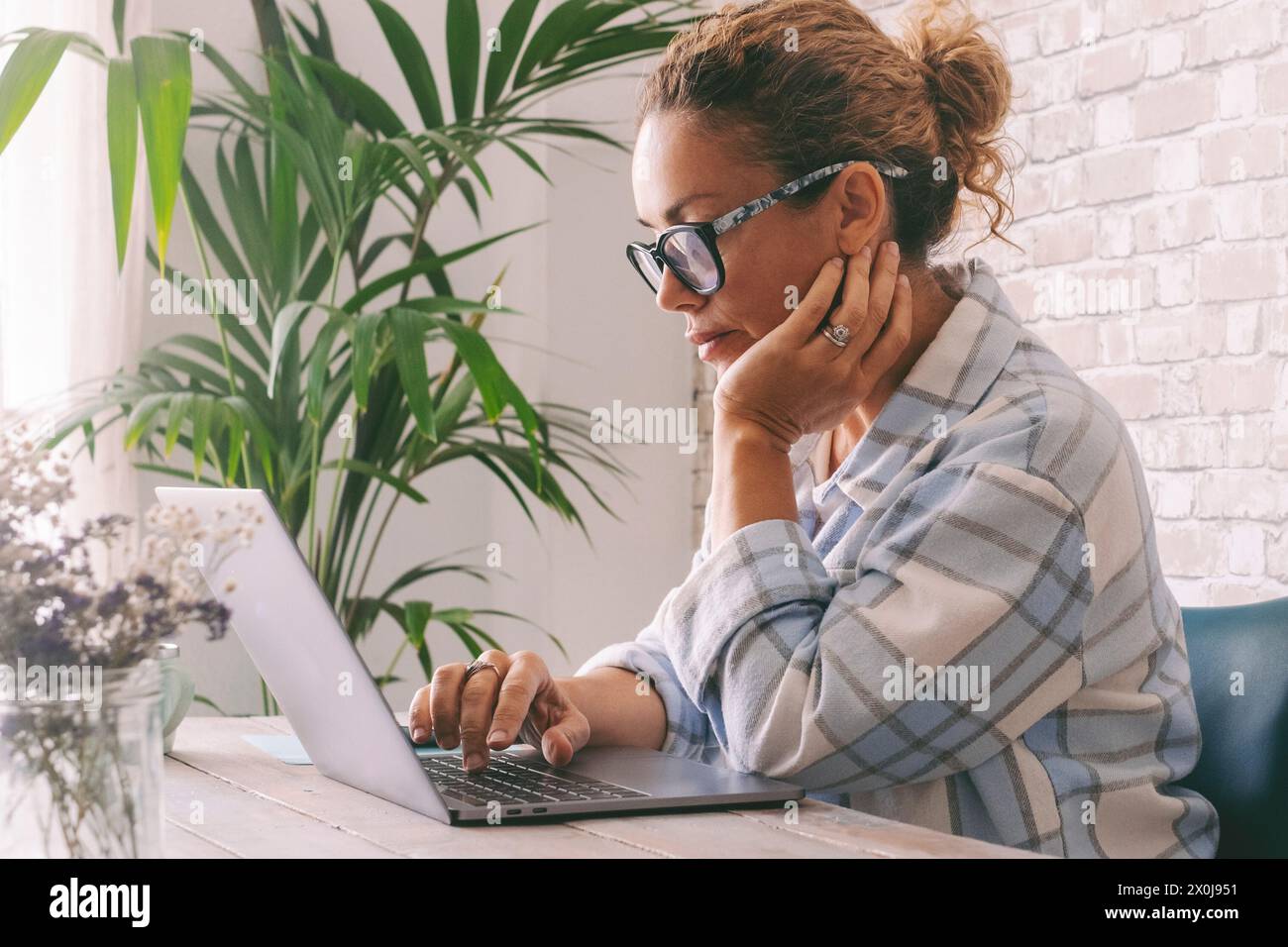 Donna freelance professionista concentrata che utilizza il notebook a casa in ufficio. Persone e lavoro digitale intelligente online occupazione di lavoro. Femmina scrive sul computer con espressione preoccupata Foto Stock