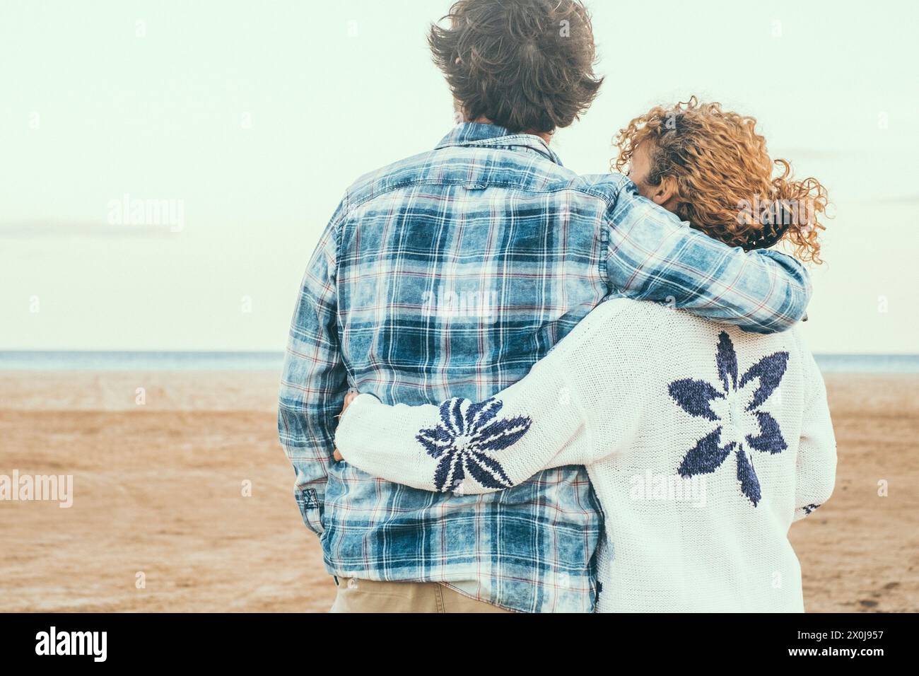 Ritratto di coppia innamorata vista posteriore ammirando la spiaggia e l'oceano abbracciando con amore. Vita romantica in vacanza invernale. Persone in rapporto abbracciare. Concetto di amore e di Unione Foto Stock