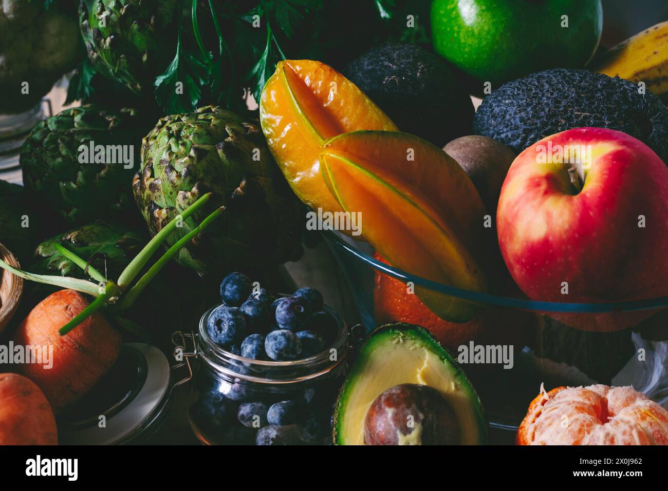 Un mix di frutta e verdura colorate con colori blak scuri sul tavolo. Concetto di stile di vita sano e piano nutrizionale dieta. Ingredienti per insalate e prodotti biologici naturali Foto Stock