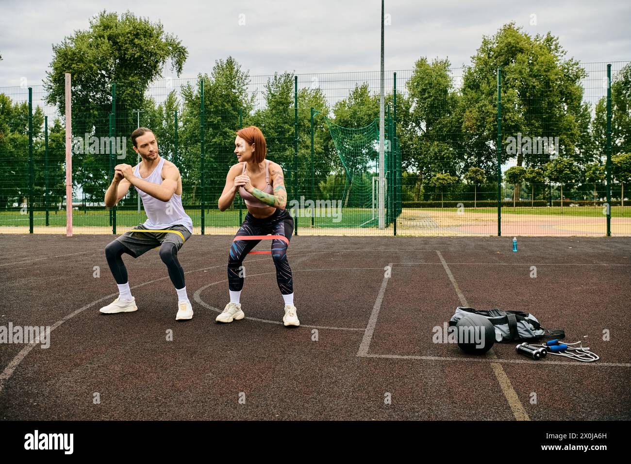 Un personal trainer motiva una donna mentre si allenano con bande di resistenza Foto Stock