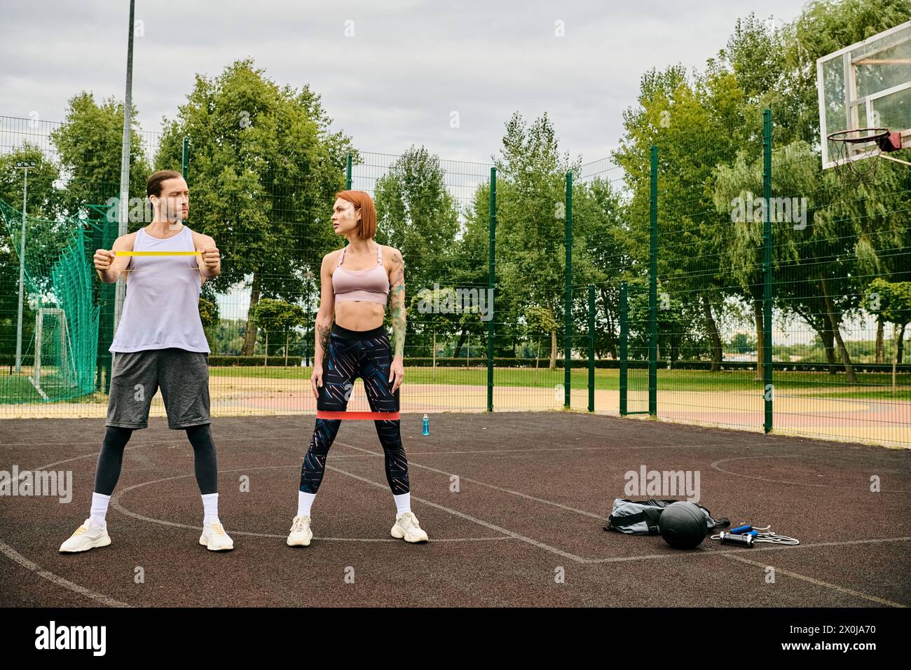 Un uomo e una donna nell'abbigliamento sportivo si allenano in campo mostrando determinazione e motivazione. Foto Stock