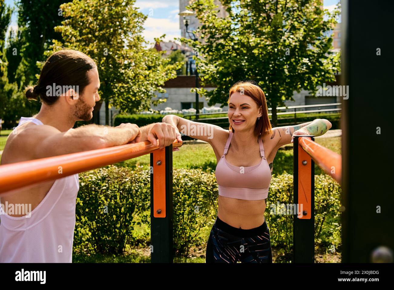 Un uomo e una donna determinati, in abbigliamento sportivo, si allenano insieme all'aperto, mostrando motivazione e concentrazione. Foto Stock