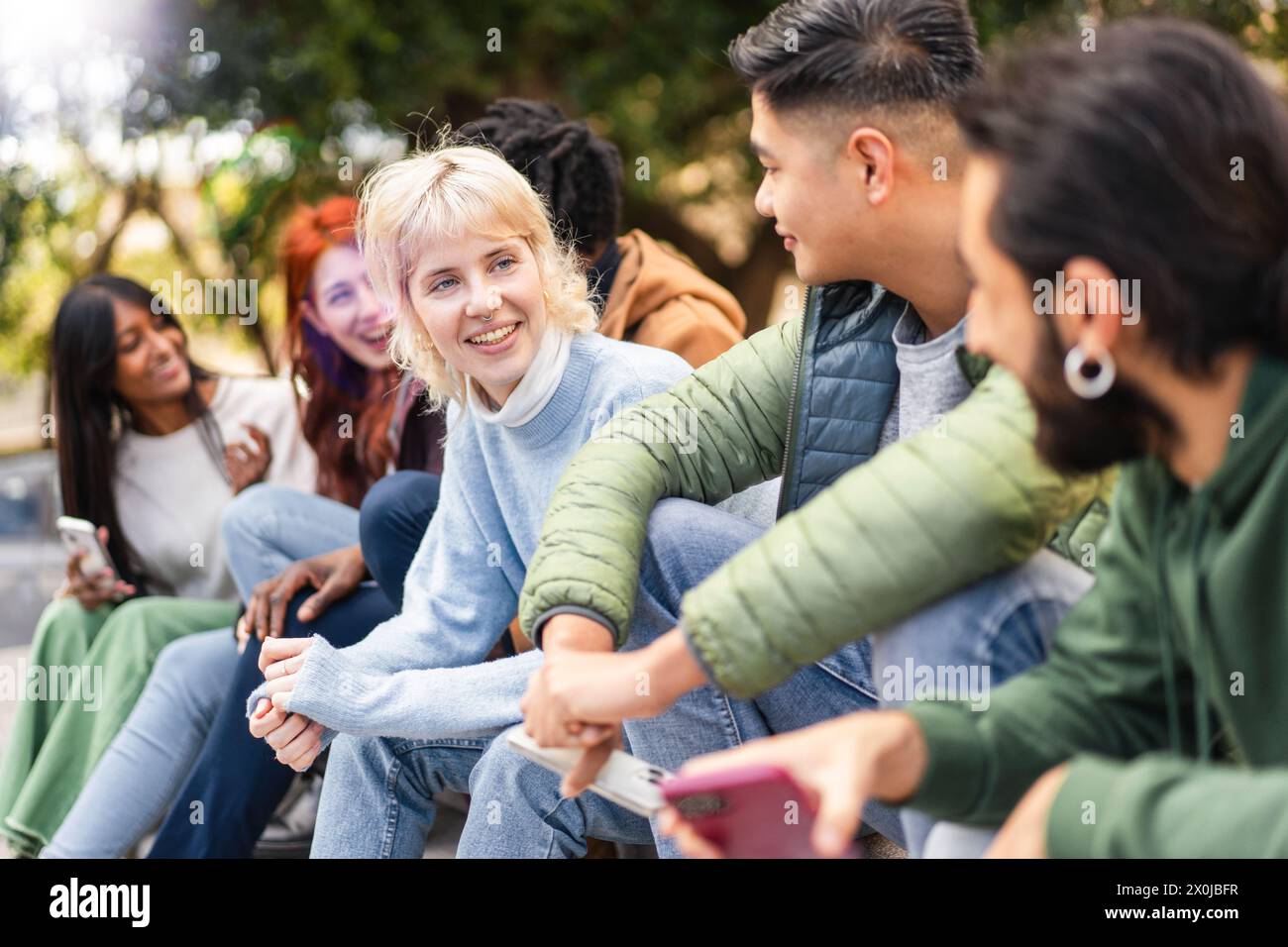 Un gruppo multiculturale di studenti universitari gode di una vivace discussione e di risate condivise in un campus all'aperto - amici che si riuniscono insieme, youthfu Foto Stock