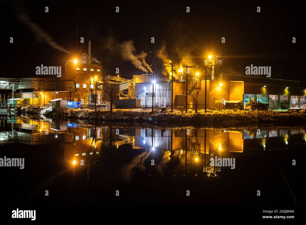 Fabbrica di carta di notte. Foto invernale di una piccola fabbrica con riflessi in un lago. Scena notturna a Bengtsfors, Svezia Foto Stock