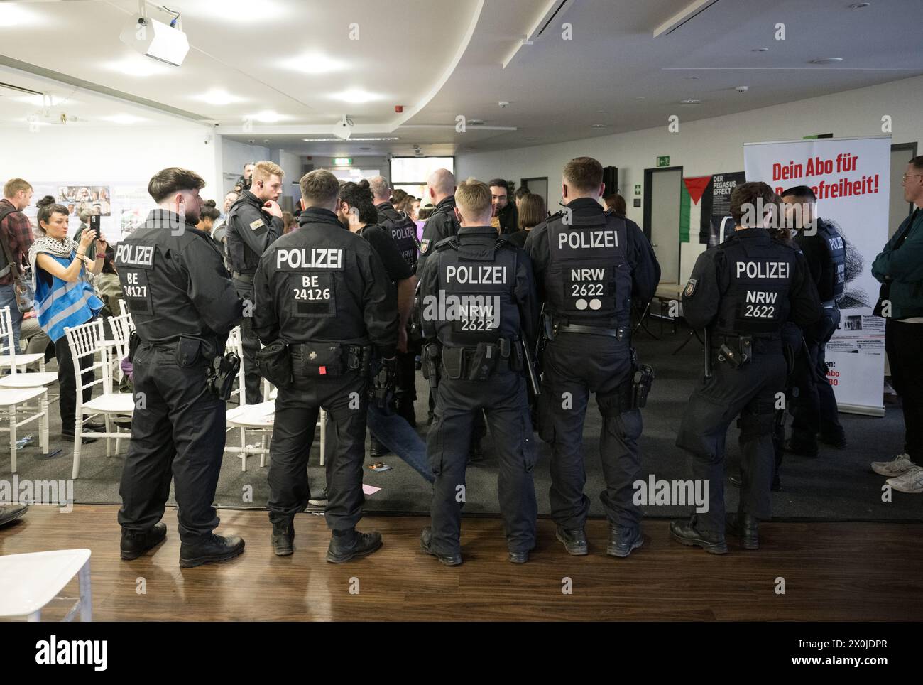 Berlino, Germania. 12 aprile 2024. Gli agenti di polizia stanno nella sala eventi dopo che la polizia si è sciolta il primo giorno del Congresso palestinese 2024. La polizia aveva già temporaneamente interrotto l'evento in anticipo. Il motivo di questo è stato un discorso trasmesso in video da un uomo a cui è stato vietato l'attività politica in Germania. L'evento pro-palestinese è previsto fino al 14 aprile. Crediti: Sebastian Christoph Gollnow/dpa/Alamy Live News Foto Stock