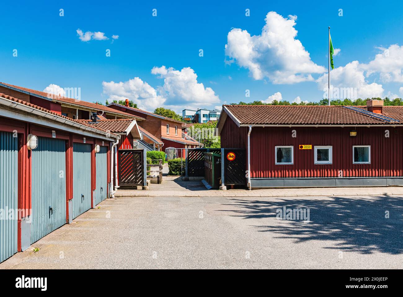 Un edificio rosso con una bandiera in alto si erge di fronte agli edifici residenziali di Mölndal, Svezia. L'impressionante facciata rossa cattura l'attenzione. Foto Stock