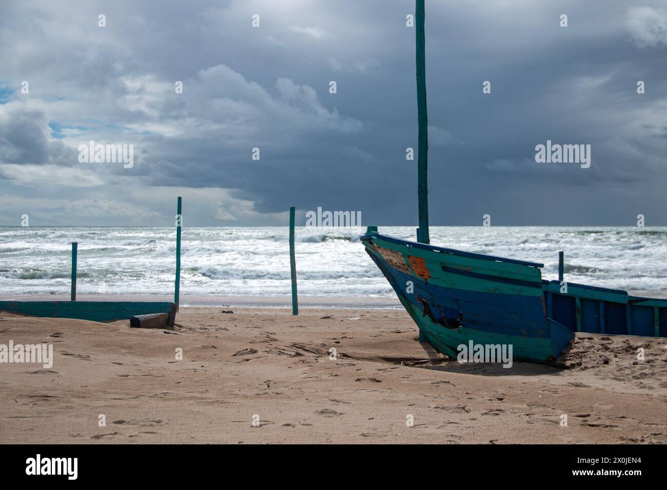 Barche di legno bloccate sulla spiaggia abbandonate e decrepite a causa del tempo inclemente con mare agitato sullo sfondo Foto Stock
