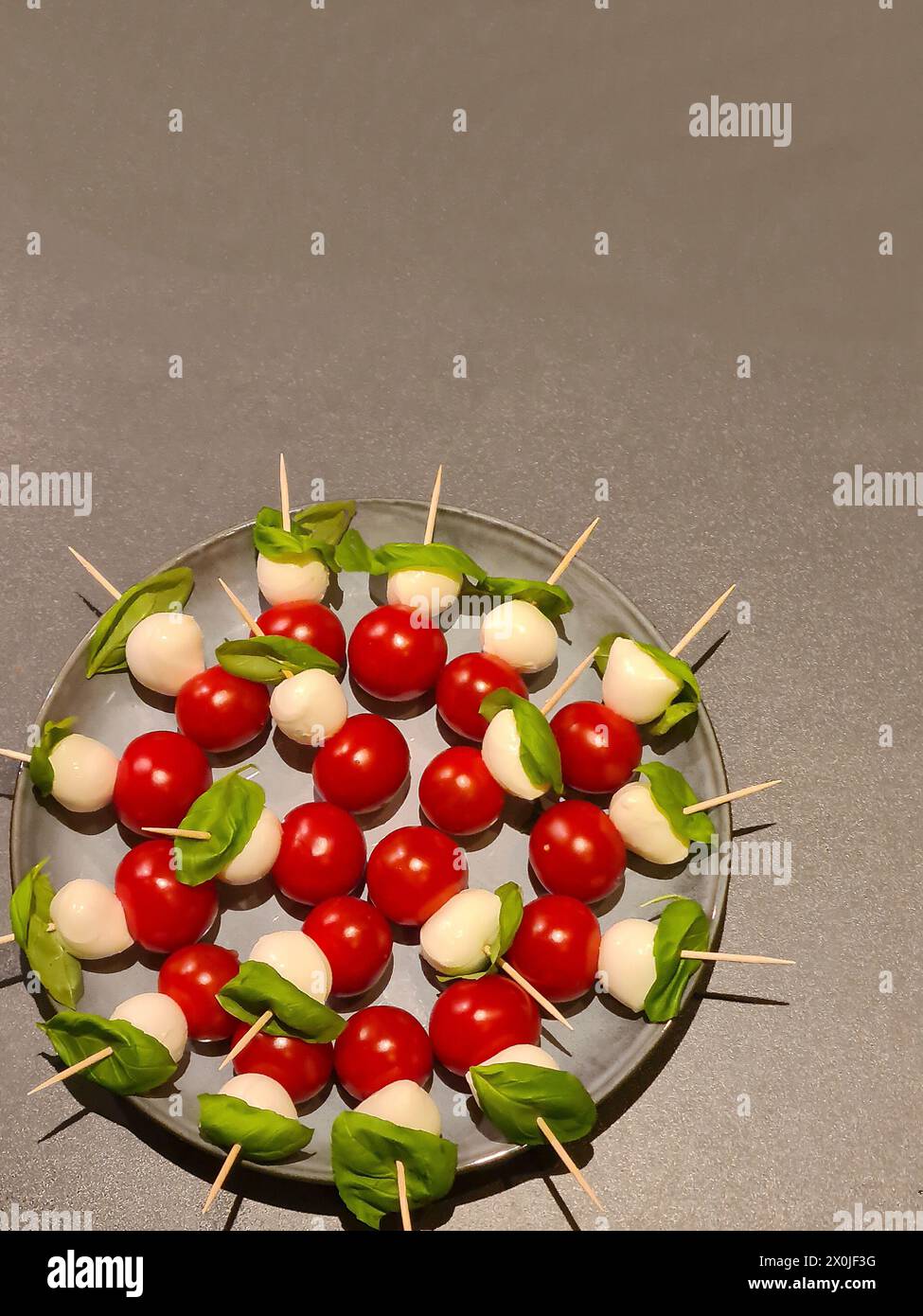 Piatto da portata con pomodori da cocktail e mozzarella di basilico come antipasto Foto Stock
