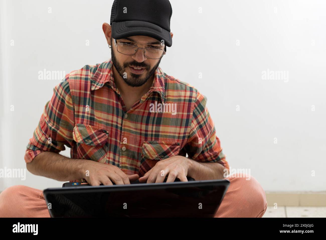 L'uomo latino-americano con il suo computer portatile è un programmatore ed è specializzato nello sviluppo web. Foto Stock