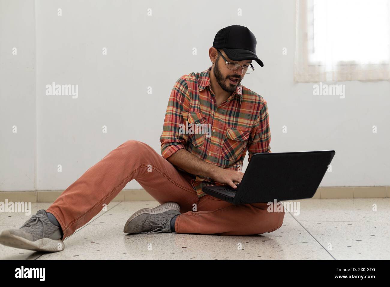 L'uomo latino-americano con il suo computer portatile è un programmatore ed è specializzato nello sviluppo web. Foto Stock