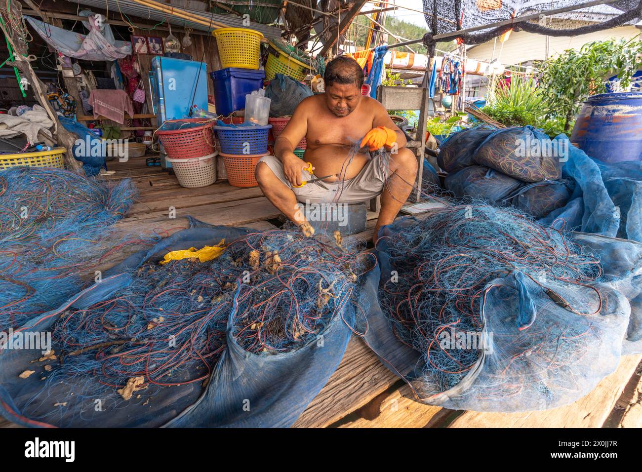 Pescatore che ripara la sua rete, villaggio di pescatori Ban Ao Salad, isola di Ko Kut o isola di Koh Kood nel Golfo della Thailandia, Asia Foto Stock