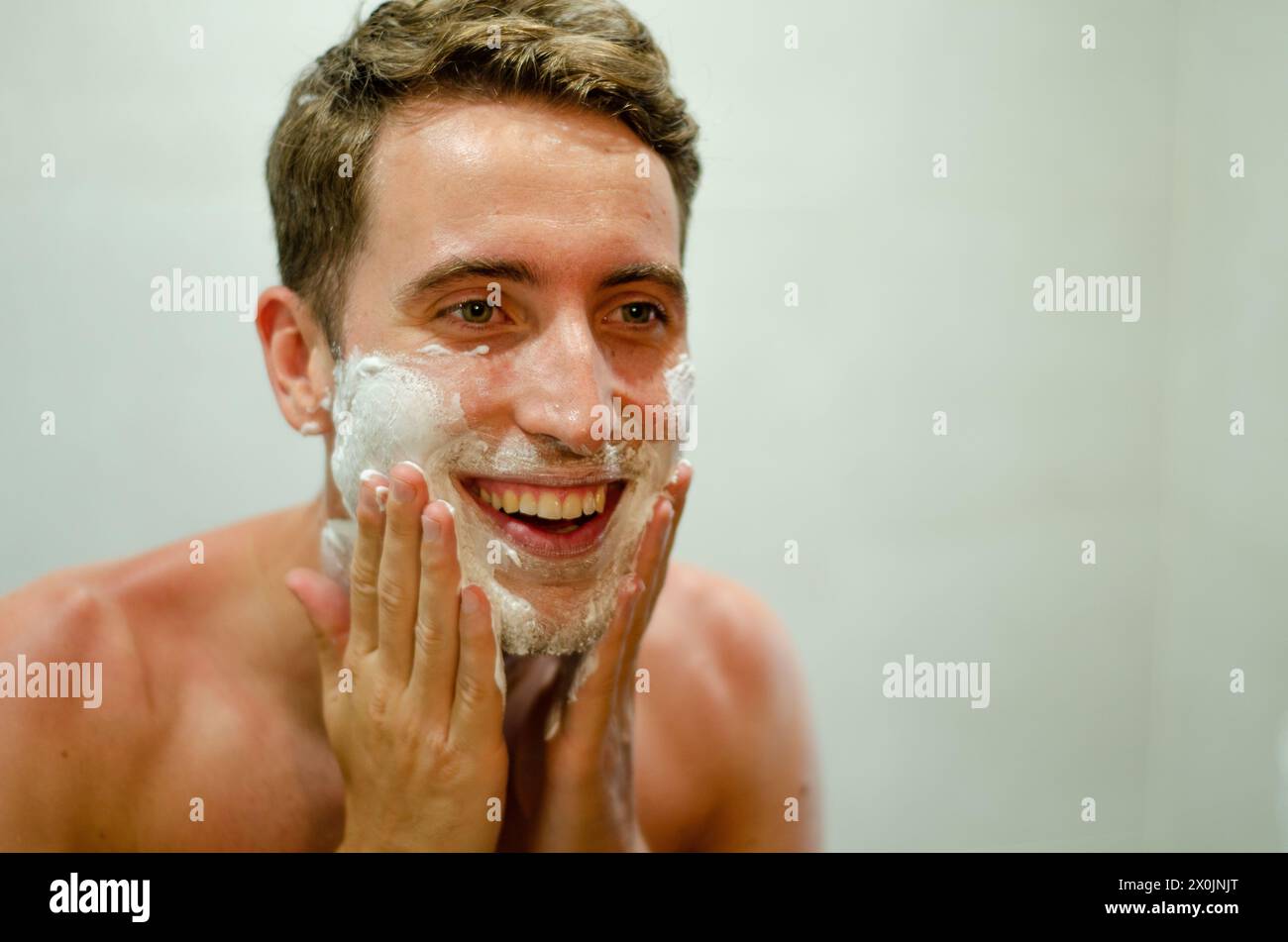 Giovane uomo che indossa la crema da barba sulla pelle Foto Stock