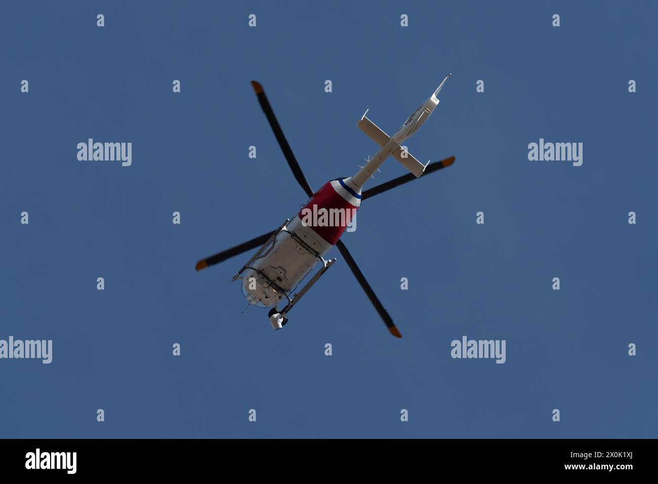 Elicottero di sorveglianza che vola sopra il cielo durante una giornata limpida e soleggiata Foto Stock