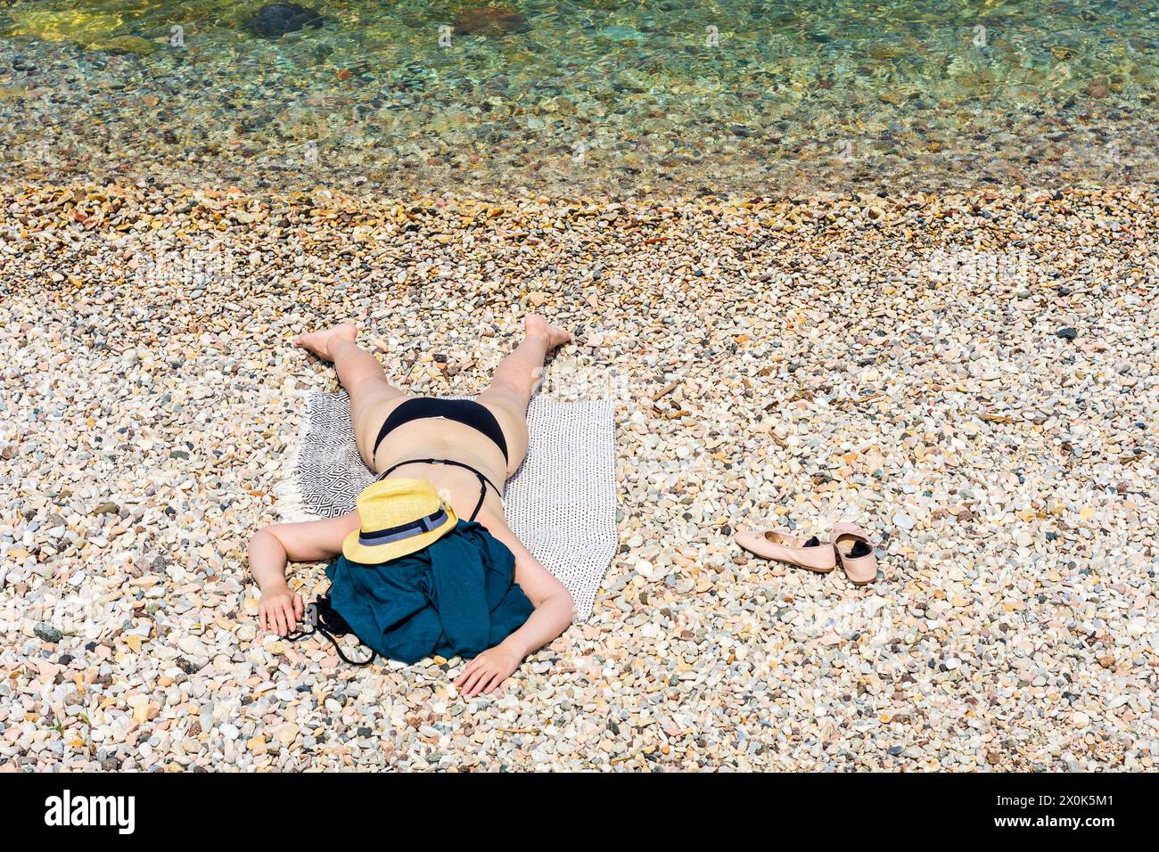 Torri del Benaco, donna sdraiata a faccia in giù sulla spiaggia, cappello da sole, bikini, Lago di Garda a Verona, Veneto, Italia Foto Stock