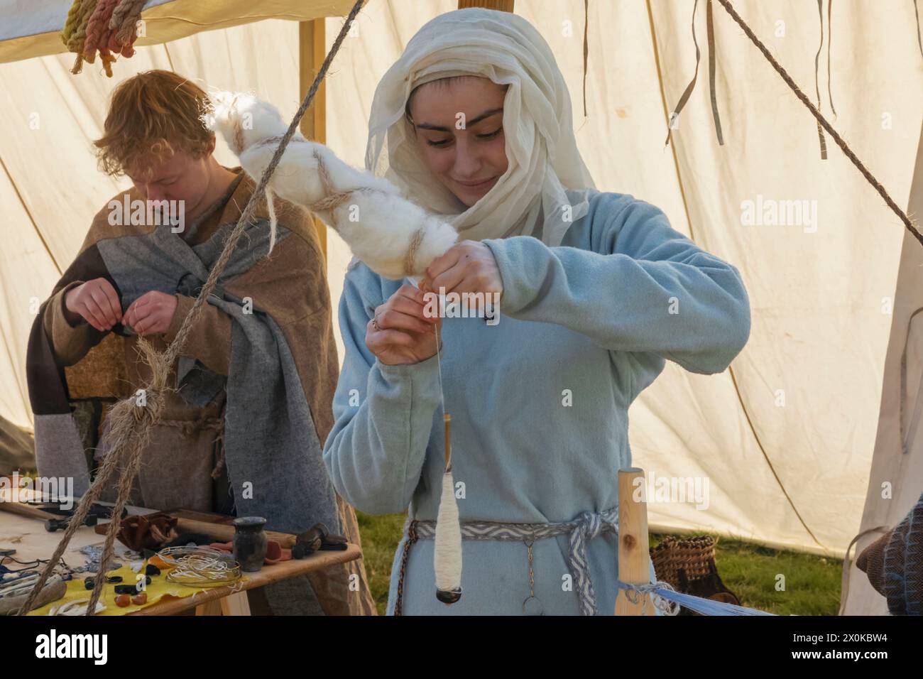 England, East Sussex, Battle, The Annual October Battle of Hastings Re-Enactment Festival, Woman in Medieval Costume Spinning Wool Foto Stock