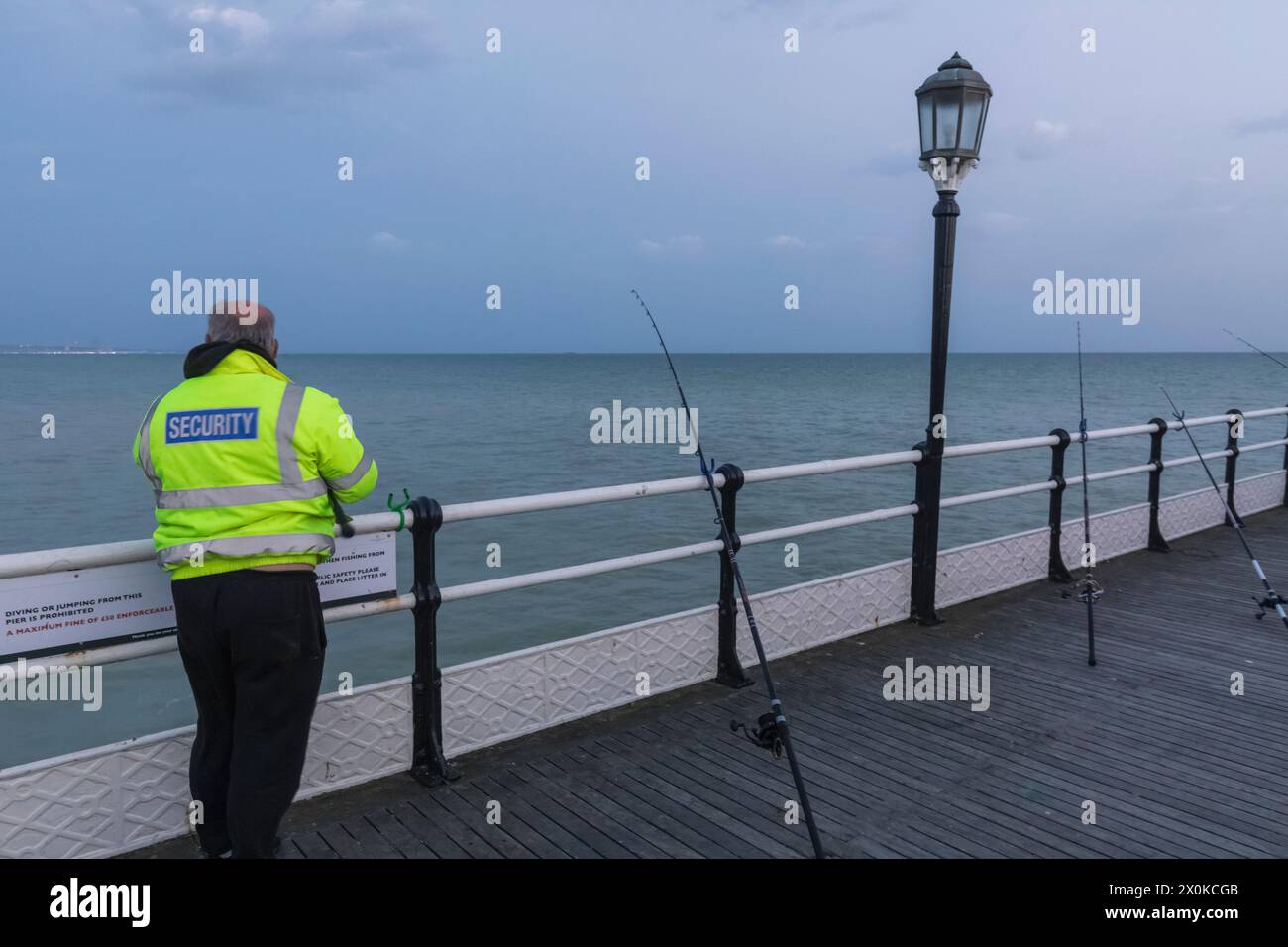 Inghilterra, West Sussex, Worthing, guardia di sicurezza che pesca sul molo di Worthing Foto Stock