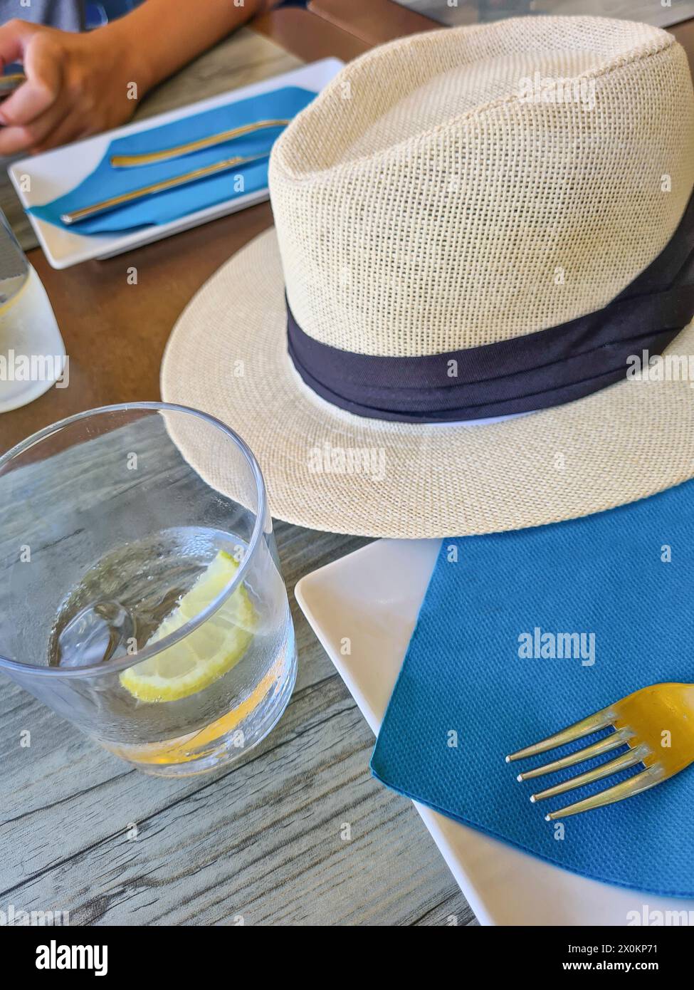 Un cappello di paglia giace all'ombra su un tavolo durante le vacanze estive, sfondo sfocato, attenzione è sul cappello di paglia come protezione solare, Maiorca, Spagna Foto Stock