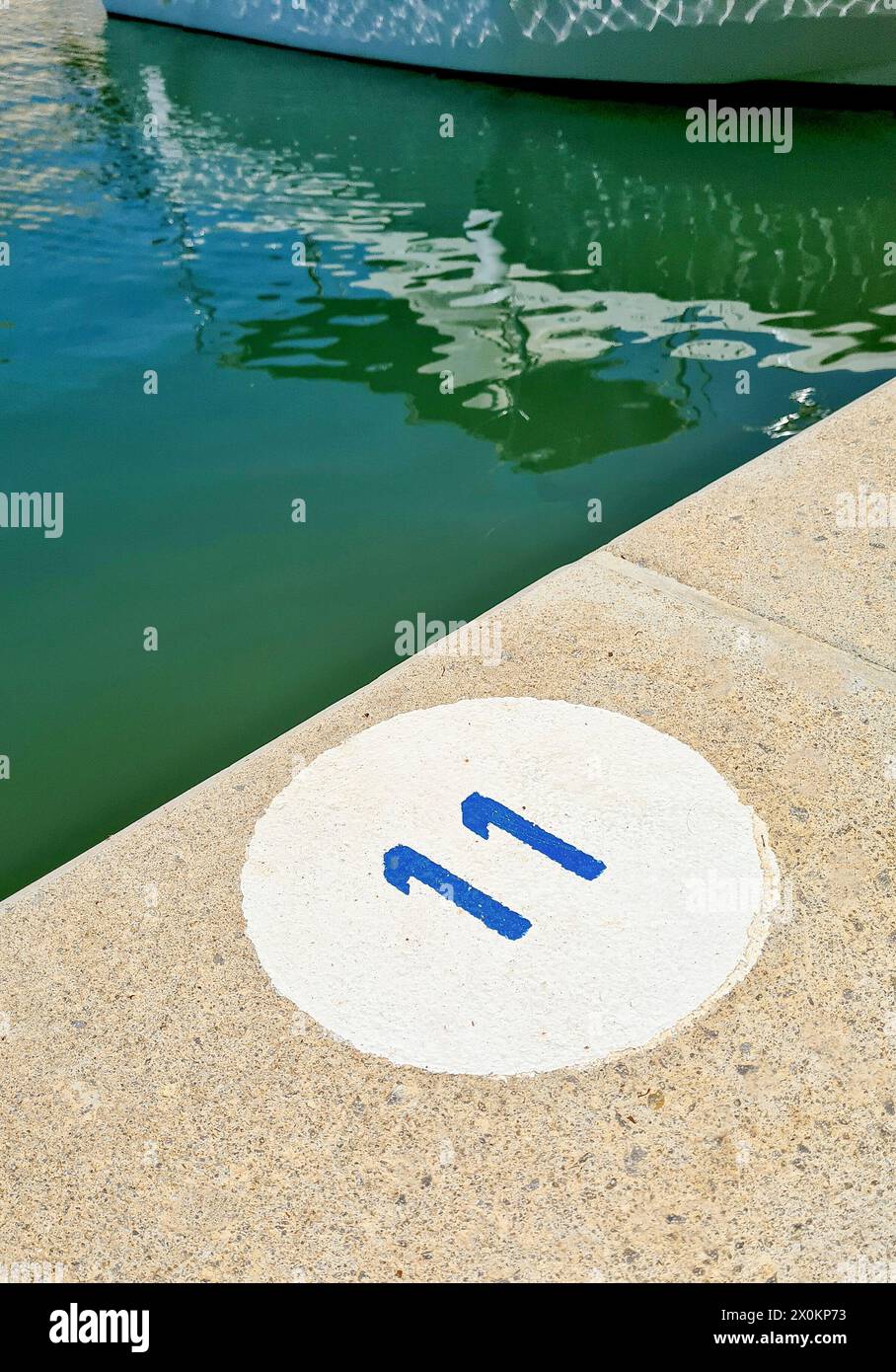 Un cerchio rotondo bianco con un numero 11 blu, che indica il pavimento in pietra, il porto, Maiorca, Spagna Foto Stock
