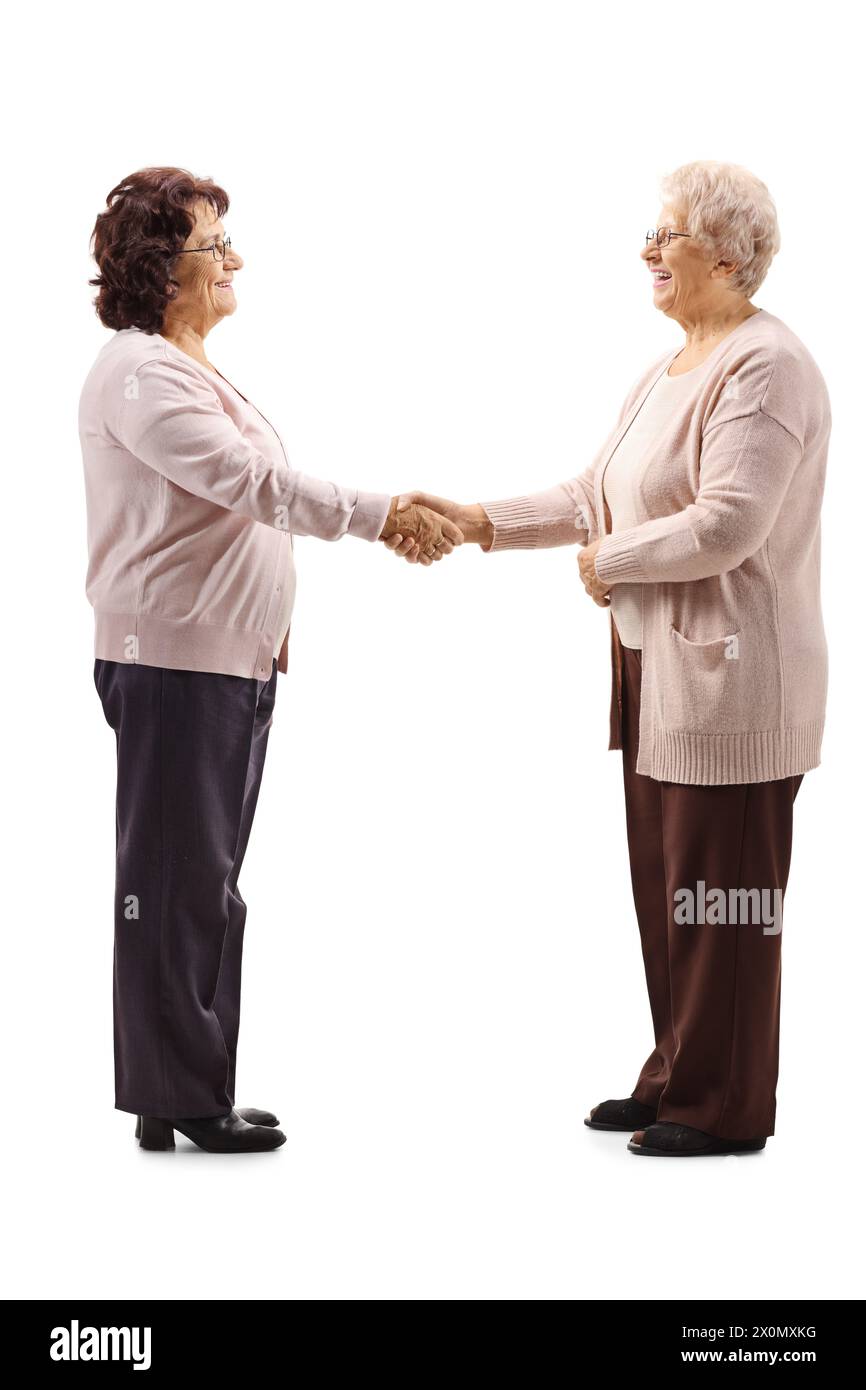 Immagine a tutta lunghezza di due donne anziane che stringono le mani isolata su sfondo bianco Foto Stock