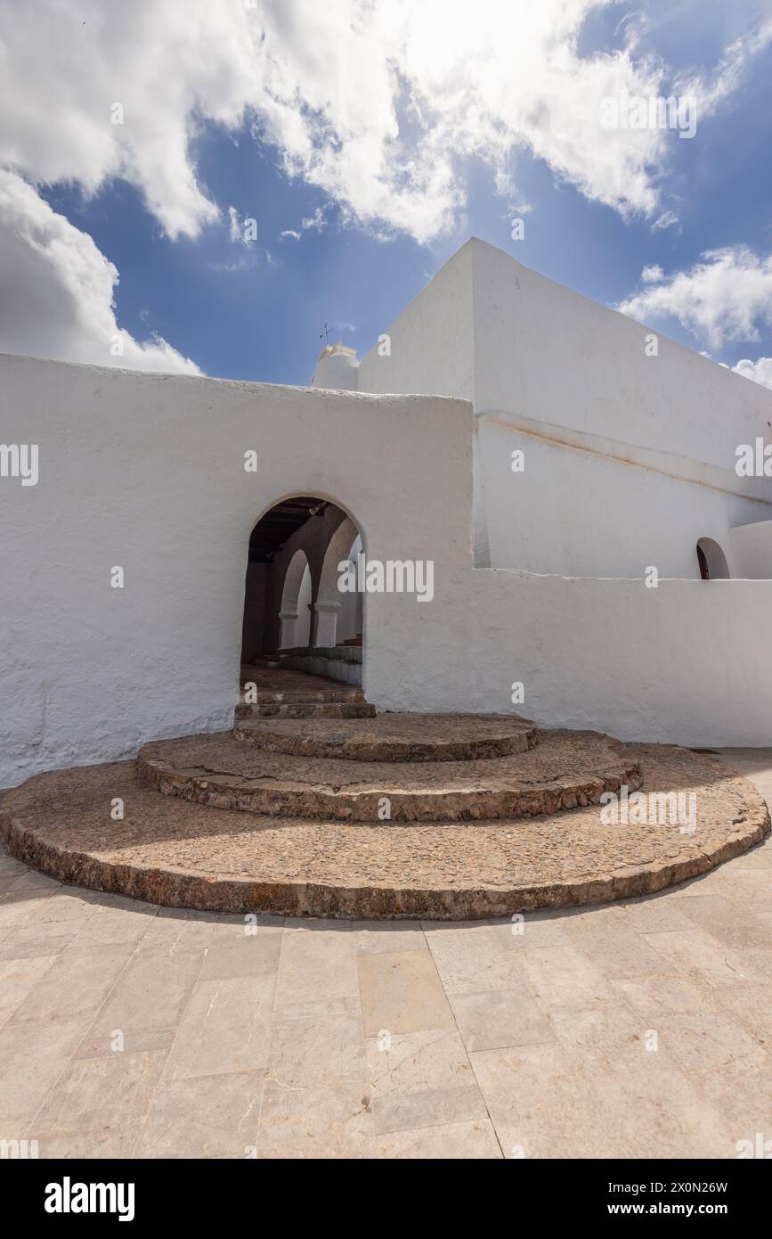 Gradini di pietra semicircolari portano a un portale ad arco nella chiesa bianca di Puig de Missa, Santa Eularia des Riu, Ibiza, Spagna. Foto Stock