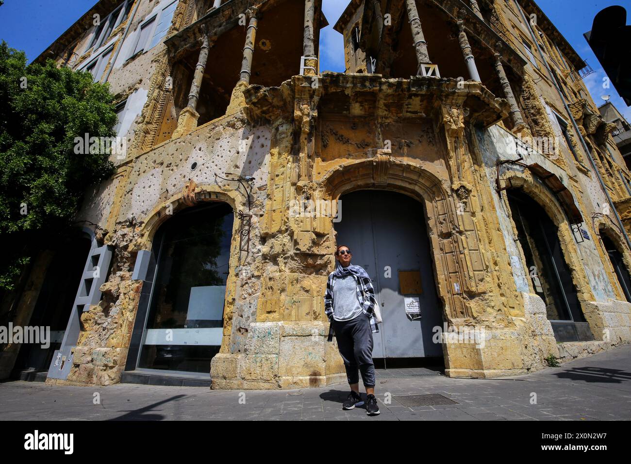 11 aprile 2024, Beirut, Beirut, Libano: NADWA ABBOUD, 59, un ex combattente sciita musulmano del partito comunista libanese si trova di fronte al famoso edificio Beit Beirut, che è diventato un museo e un centro culturale urbano che ha lo scopo di ritrarre la storia di Beirut, con particolare attenzione alla guerra civile libanese. Beit Beirut era un posto del NADWA, situato sulla linea di battaglia che separava Beirut in due metà, quando aveva solo 16 anni durante la guerra civile libanese che scoppiò il 13 aprile 1975. Quarantanove anni dopo l'inizio della guerra la NADWA si sente ancora spaventata e g Foto Stock