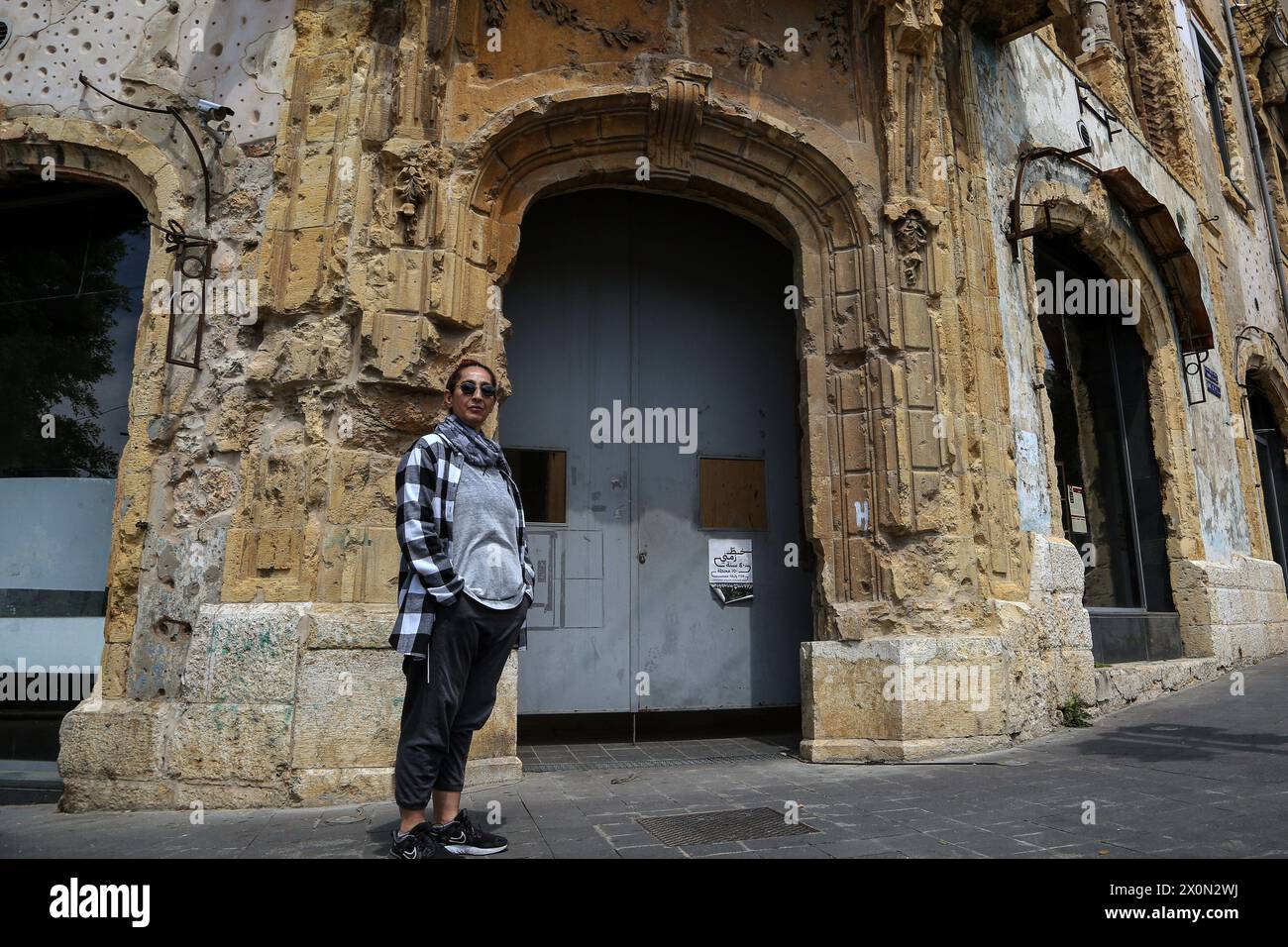 11 aprile 2024, Beirut, Beirut, Libano: NADWA ABBOUD, 59, un ex combattente sciita musulmano del partito comunista libanese si trova di fronte al famoso edificio Beit Beirut, che è diventato un museo e un centro culturale urbano che ha lo scopo di ritrarre la storia di Beirut, con particolare attenzione alla guerra civile libanese. Beit Beirut era un posto del NADWA, situato sulla linea di battaglia che separava Beirut in due metà, quando aveva solo 16 anni durante la guerra civile libanese che scoppiò il 13 aprile 1975. Quarantanove anni dopo l'inizio della guerra la NADWA si sente ancora spaventata e g Foto Stock