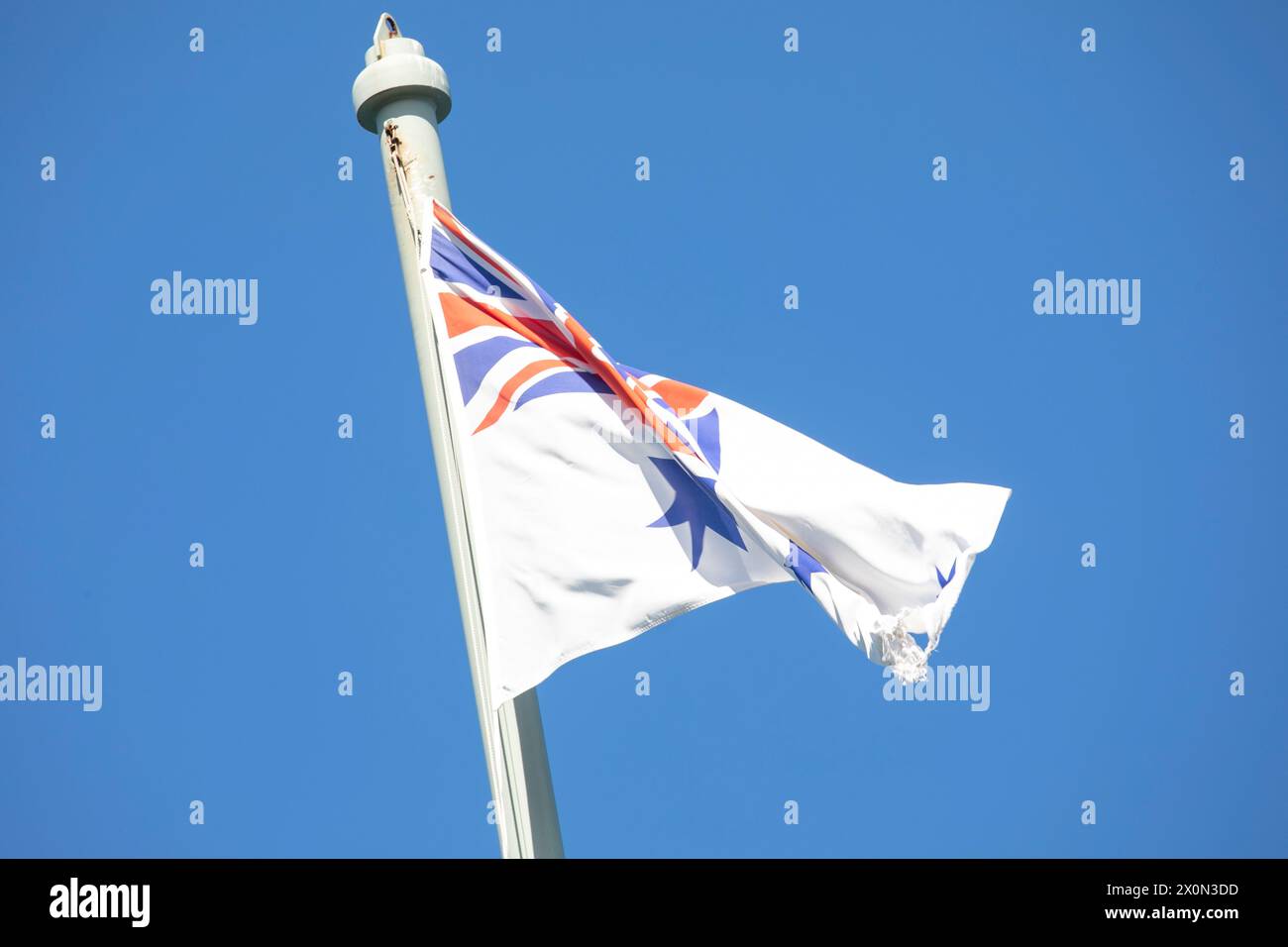 Bandiera australiana White Ensign che sventola in cima all'albero commemorativo HMAS Sydney 1 presso il forte Bradleys Head sulla riva nord di Sydney, NSW, Australia Foto Stock