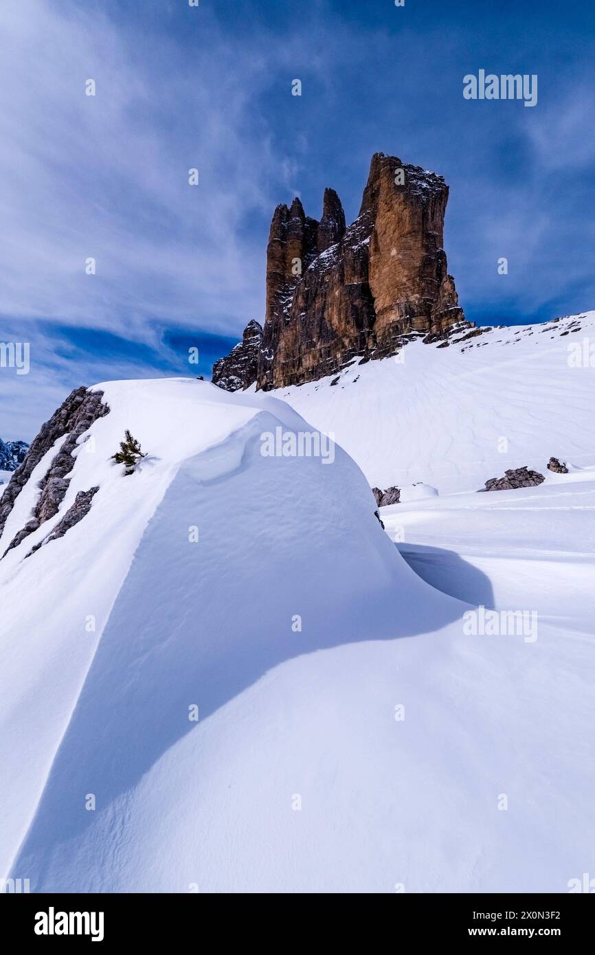 Ciaspolate che creano strutture artistiche nel Parco naturale delle tre Cime in inverno, le cime delle tre Cime di Lavaredo in lontananza, viste da forcella Lavar Foto Stock