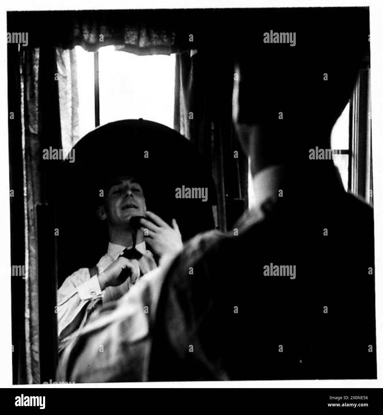 Un soldato dell'Ottava Armata in congedo regola il collare e la cravatta, illustrando il ritorno all'abbigliamento civile dopo il servizio militare, British Army. Foto Stock