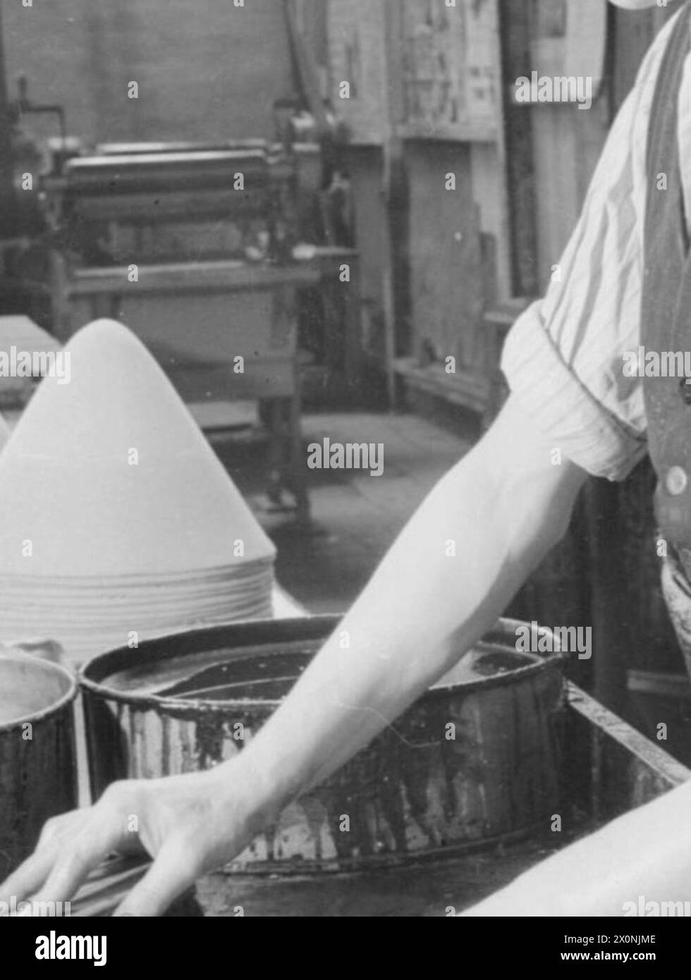 Fotografia di un operaio di una fabbrica di cappelli in Gran Bretagna, nel 1940, che sparge un guscio su un cappuccio di feltro per i cappelli della polizia a cavallo canadese. Foto Stock
