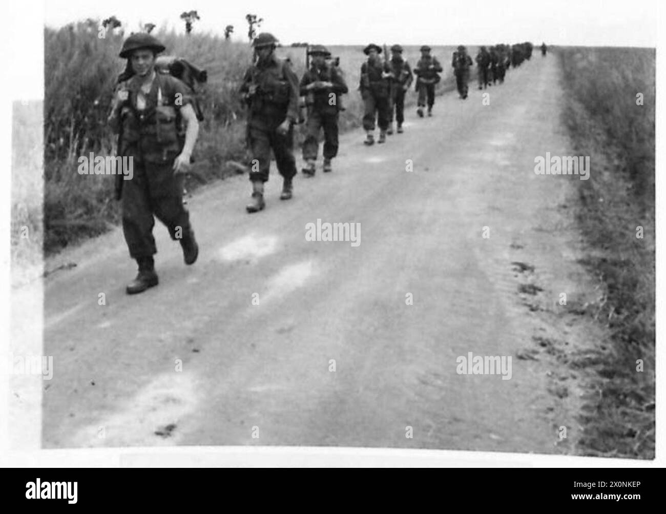 Fotografia che mostra la fanteria canadese che marcia in ordine esteso su una strada verso la linea del fronte nell'area di Camaes, che illustra il movimento e lo spiegamento delle truppe durante il 1944-1945. Foto Stock
