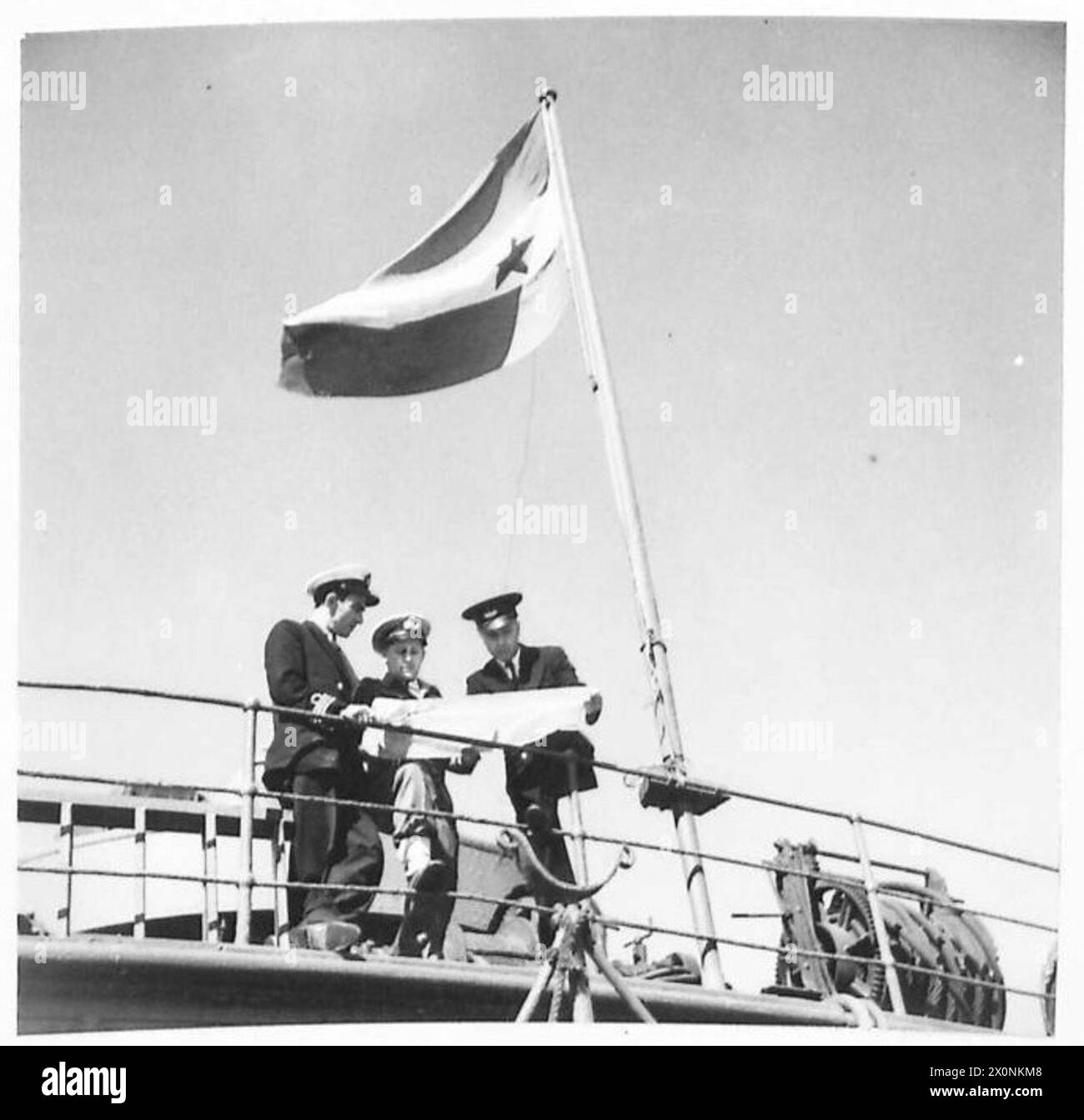 Fotografia degli ufficiali iugoslavi a bordo del piroscafo Justopic e dell’ufficiale di collegamento del trasporto marittimo britannico che ispeziona il contenuto elencato della nave per operazioni di soccorso in Jugoslavia. L'immagine mostra la bandiera jugoslava. Negativo fotografico dell'esercito britannico. Foto Stock