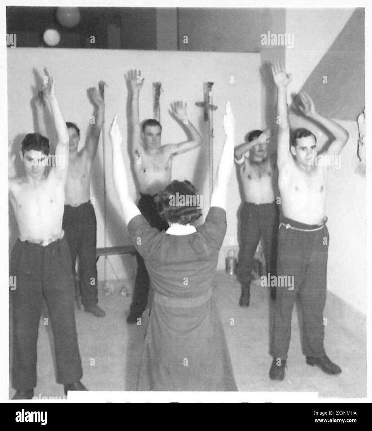 La signorina Margaret Ellis, fisioterapista americana, assiste un paziente che si riprende dalle ferite in un ospedale dell'esercito britannico, illustrando il supporto medico e la riabilitazione. Foto Stock