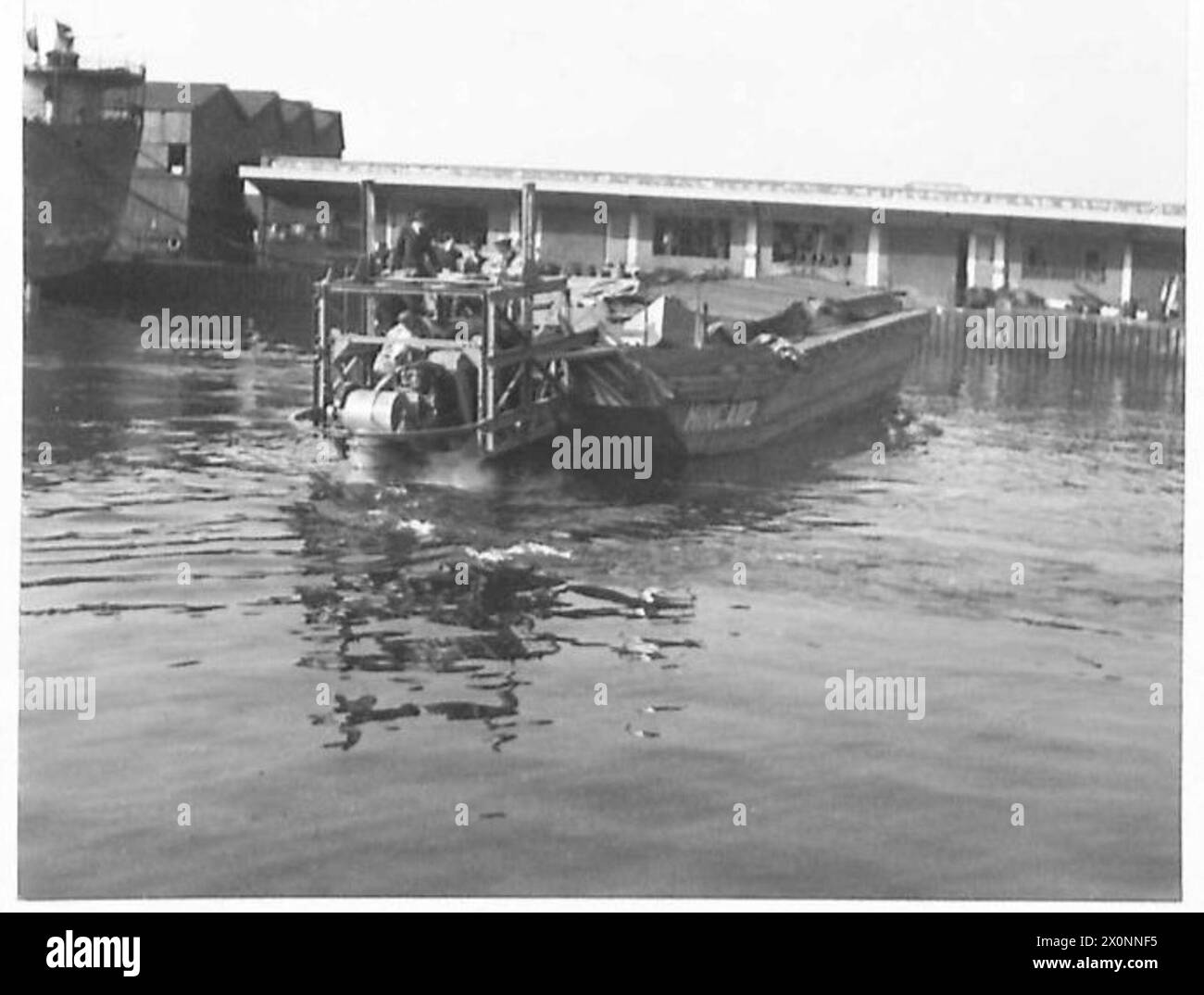 La fotografia mostra la vista a poppa della chiatta Minca in corso durante i test del motore fuoribordo. L'immagine è un negativo fotografico, associato all'esercito britannico. Foto Stock