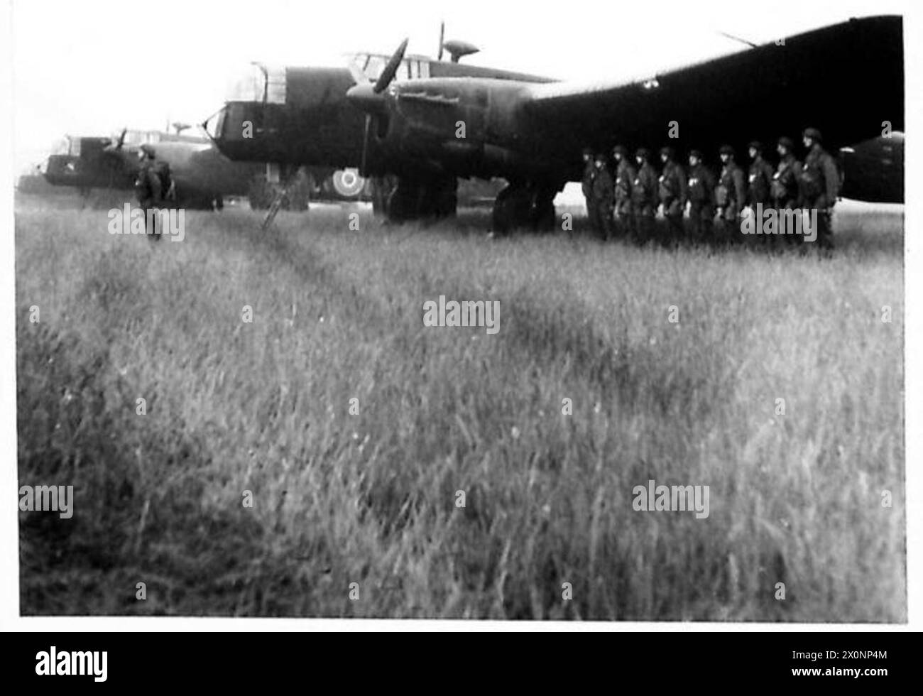 Negativo fotografico che mostra il re e la regina che ispezionano le truppe paracadute formate in parata accanto ai loro aerei. Foto Stock