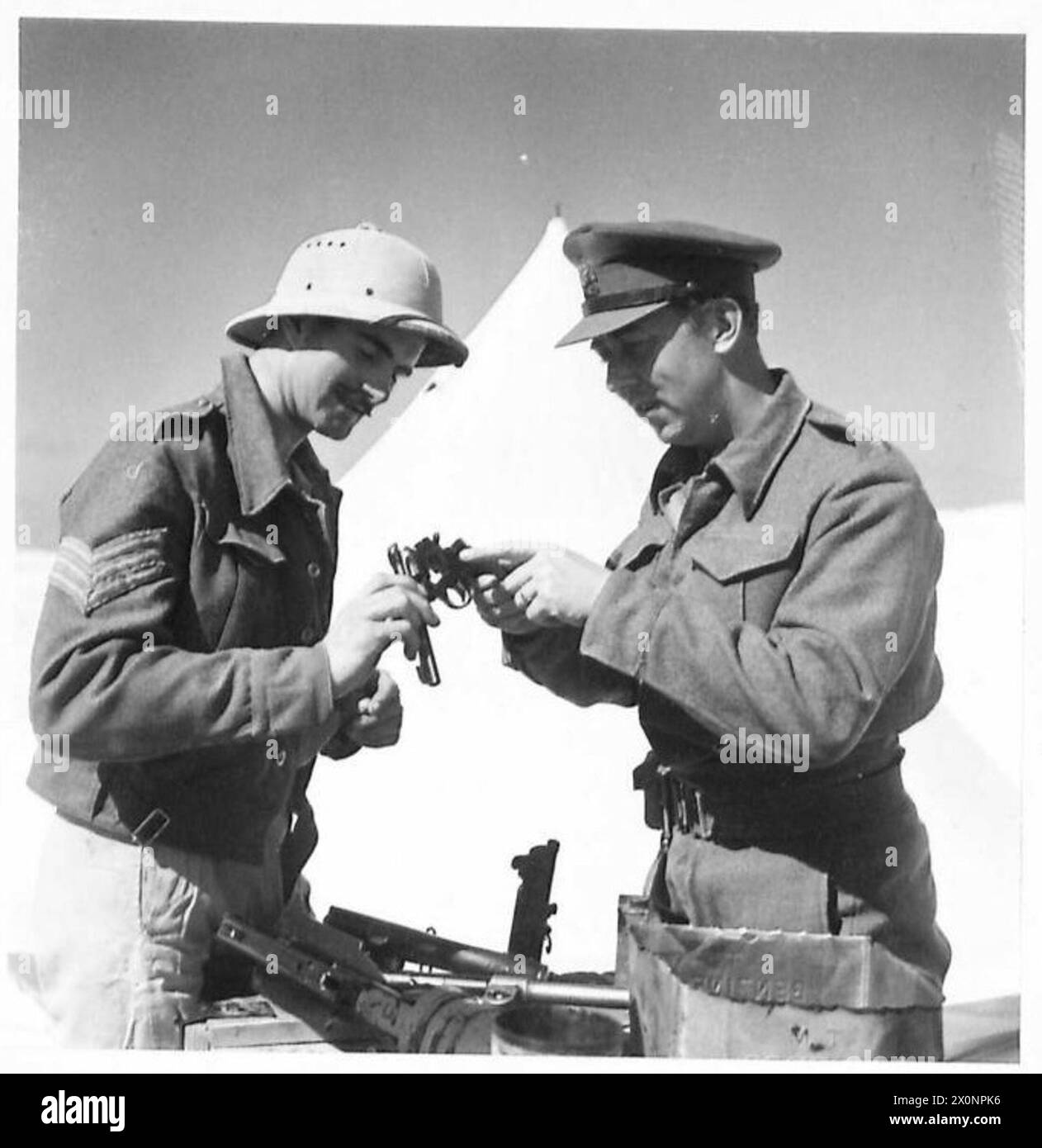 Un ufficiale porta il revolver per la riparazione in un'armeria del deserto. Negativo fotografico, British Army. Foto Stock