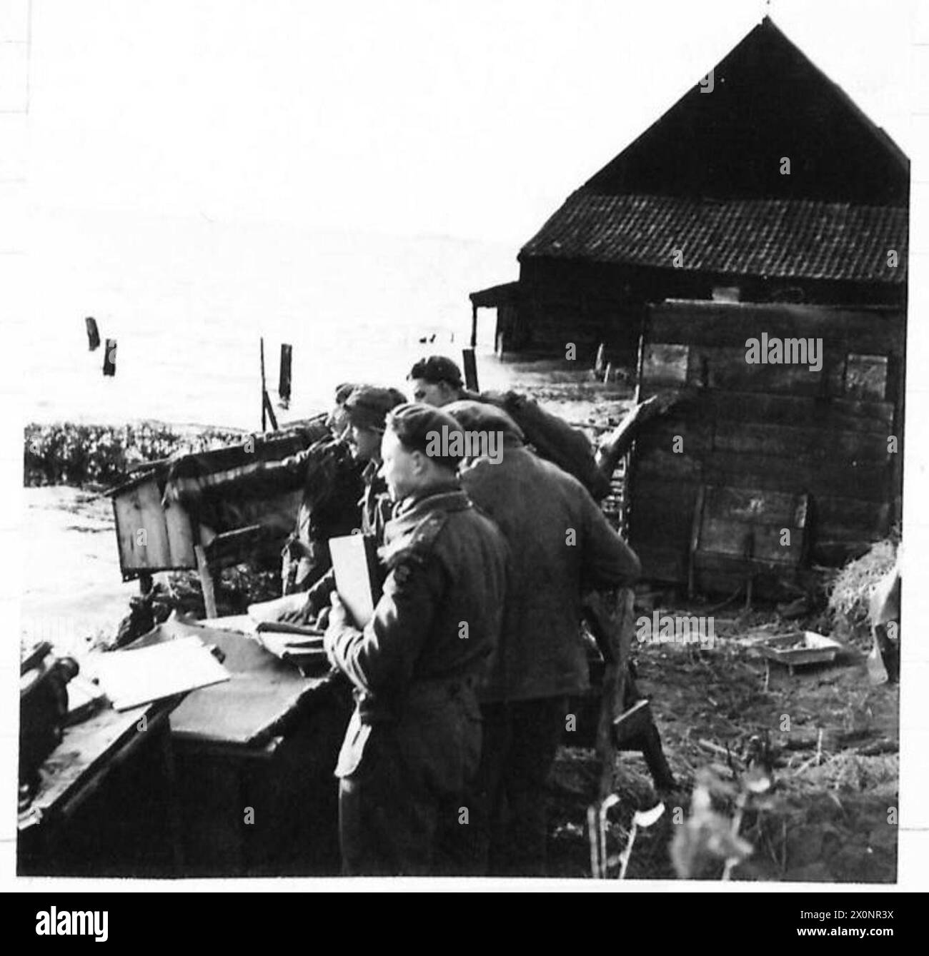 Il maggiore J.E.B. Freeman e gli ufficiali del 4th Battalion, Lincoln, 146 Brigata, 49 Divisione conferiscono per l'assalto finale a Willemstad, Olanda, osservando le inondazioni dopo la scadenza della tregua. Negativo fotografico, British Army, 21st Army Group. Foto Stock